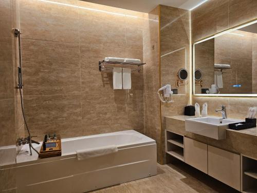 a bathroom with a tub and a sink and a mirror at Hompton Hotel by the Beach in George Town