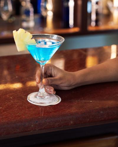 a person holding a blue drink in a martini glass at De Garland Palolem - AM Hotel Kollection in Palolem