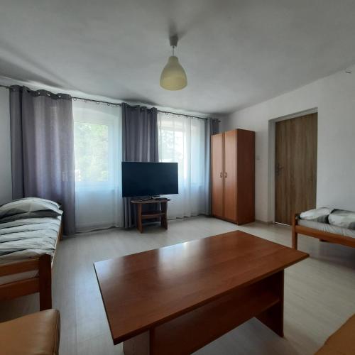 a living room with a wooden table and a television at Na Spokojnej Rodzinne Wakacje in Pogorzelica