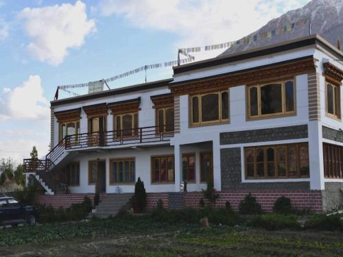 a large white house with a porch at POP HOME 81129A Skayil Guest House in Nubra