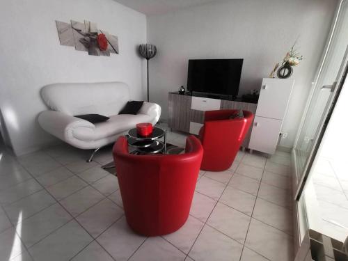 un salon avec deux chaises rouges et une télévision dans l'établissement 039 Marina Bay 403, au Cap d'Agde