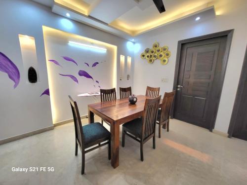 a dining room with a wooden table and chairs at BnBBuddy Athulyam 3 BHK Homestay, Shalimar Bagh in New Delhi
