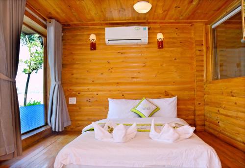una camera con un letto bianco su una parete in legno di Phu Ninh Lake Resort & Spa a Tam Kỳ