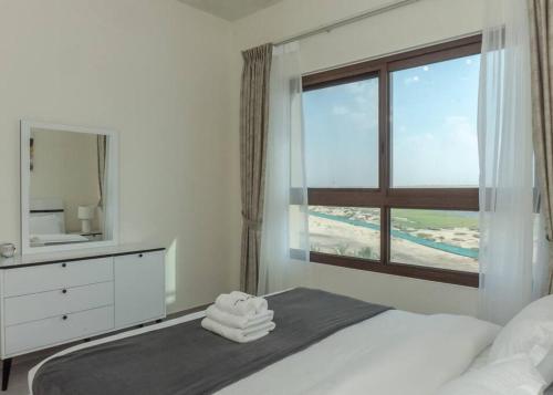 a bedroom with a bed with a mirror and a window at StoneTree - Furnished 1BR in Peaceful Community in Dubai