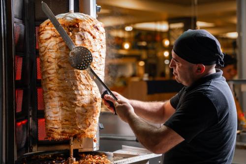 a man is cooking a large piece of meat at SUN HEAVEN FAMILY & SPA in Alanya