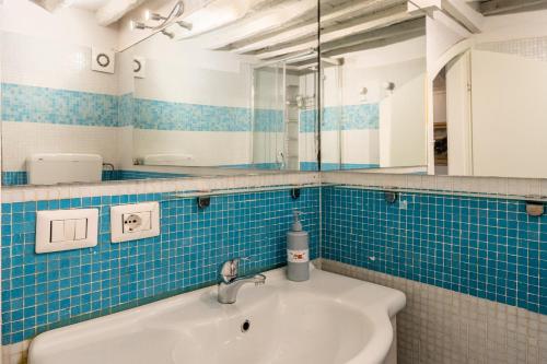 een blauw betegelde badkamer met een wastafel en een spiegel bij Elisa loft davanti alle Mura Lucca in Lucca