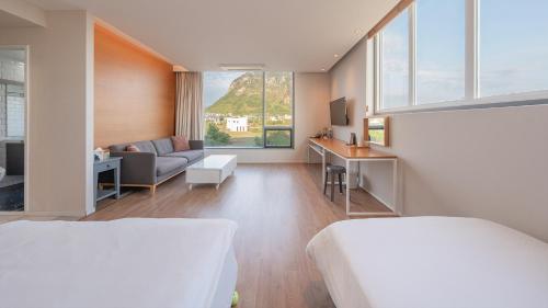 a bedroom with two beds and a living room with a couch at Lucid M in Seogwipo