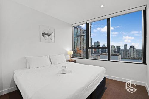 a bedroom with a white bed and a large window at Rest SkyHigh Melbourne Qtr Collection in Melbourne