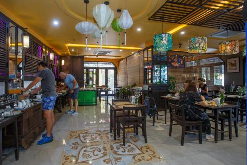 a restaurant with people sitting at tables and a bar at Hoianan Boutique Hotel in Hoi An
