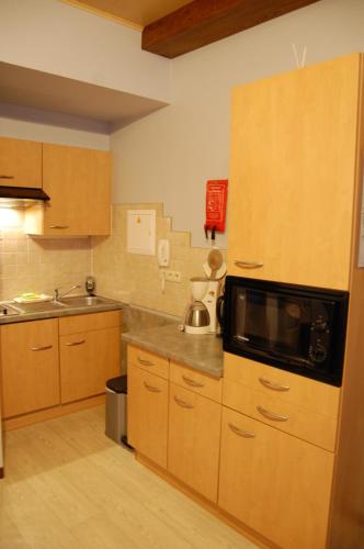 a kitchen with wooden cabinets and a microwave at Appart Hotel Au Pied de Vigne in Vresse-sur-Semois