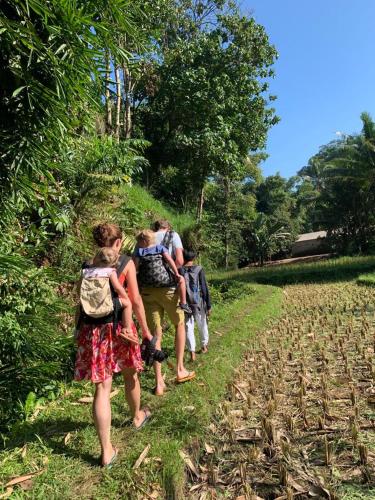 a group of people walking down a field at EDRIAN BUNGALOWS in Tetebatu