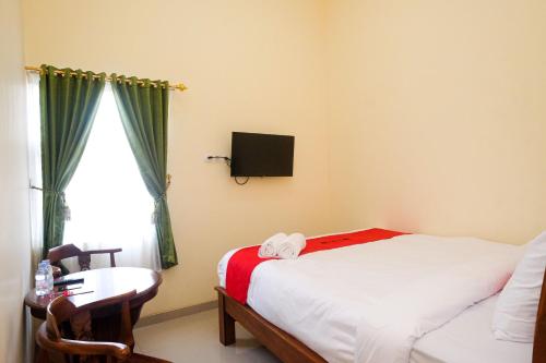 um quarto com uma cama, uma secretária e uma janela em RedDoorz Syariah @ Klodran Solo em Kadipiro