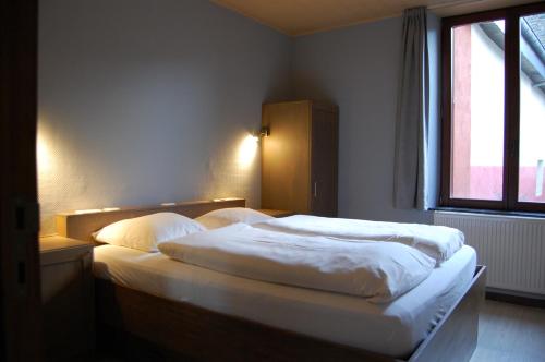 a bedroom with a bed with white sheets and a window at Appart Hotel Au Pied de Vigne in Vresse-sur-Semois
