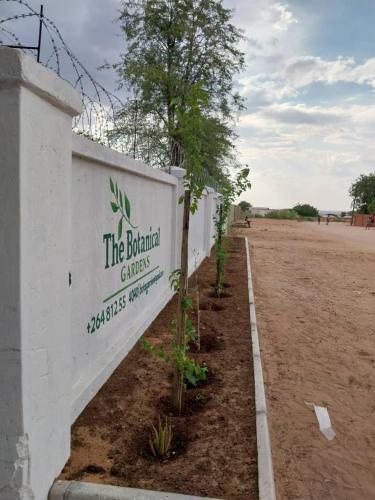 uma parede branca com um sinal que diz o jardim bíblico em The Botanical Gardens em Rundu