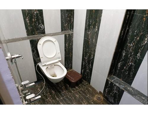 a dirty bathroom with a toilet in a stall at Hotel Khard Palace, Jhansi in Jhānsi