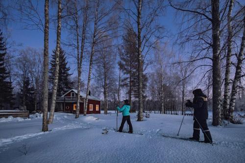 two people on skis in the snow in front of a house at Kalix Riverside inn in Kalix