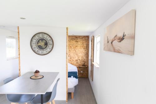 comedor con mesa y reloj en la pared en Mobil Home à la Ferme, en Fiennes