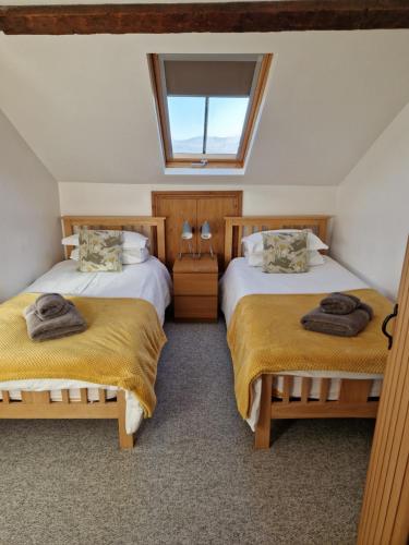 two beds in a room with a window at Rainors farm cottage in Gosforth