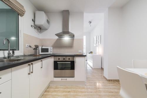 uma cozinha com armários brancos e um lavatório em Home2Book Charming Apartments La Naval La Isleta em Las Palmas de Gran Canaria