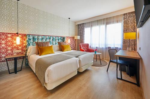 um quarto com uma cama grande, uma mesa e cadeiras em Hesperia Sevilla em Sevilha