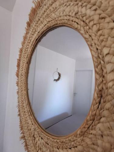 un miroir en rotin avec un bug dans la réflexion dans l'établissement Appartement accès direct à la plage, à Bernières-sur-Mer
