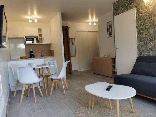 un salon avec un canapé, une table et des chaises dans l'établissement Appartement accès direct à la plage, à Bernières-sur-Mer