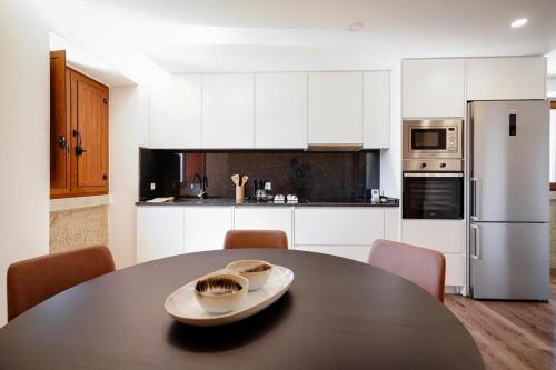 a kitchen with a black table and white cabinets at RB Ganfei House in Valença