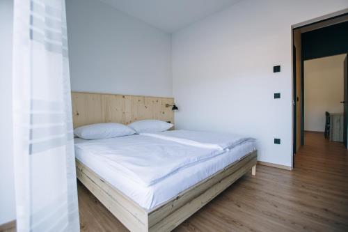 a bed with white sheets and pillows in a bedroom at Postcard Country Apartments in Spodnji Duplek