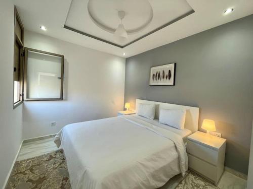 um quarto com uma grande cama branca e 2 candeeiros em A3 Appartement entièrement neuf au cœur de Témara em Temara