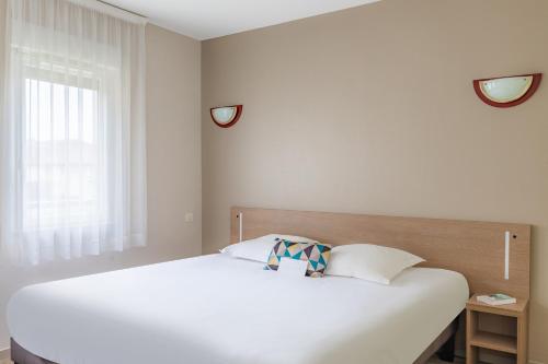 a white bed in a room with a window at Appart'City Classic Limoges in Limoges