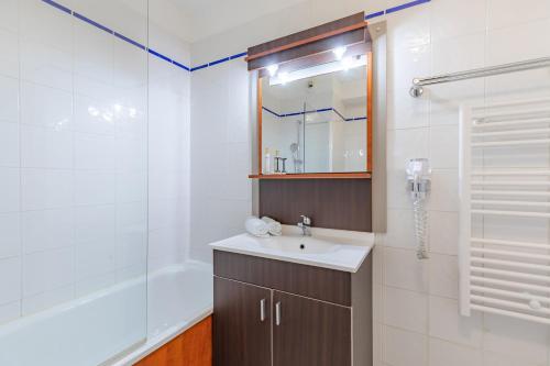 a bathroom with a sink and a shower and a mirror at Appart'City Classic Limoges in Limoges