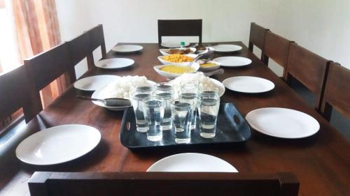 drewniany stół z białymi płytami i okularami w obiekcie Forest Edge Bungalow - Wilpattu w mieście Radagama