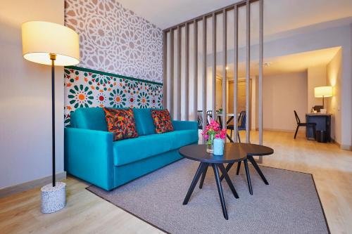 a living room with a blue couch and a table at Hesperia Sevilla in Seville