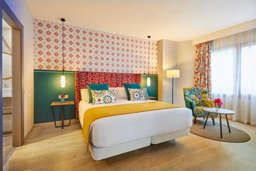 a hotel room with a bed and a chair at Hesperia Sevilla in Seville
