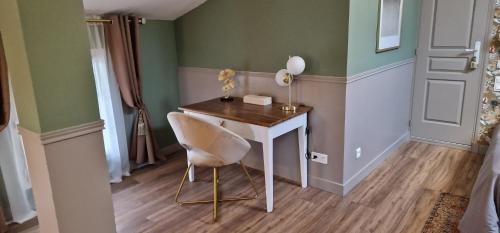 uma mesa e uma cadeira num quarto com paredes verdes em La Glycine Blanche em Pomas
