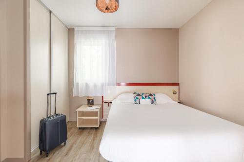 a bedroom with a large bed and a suitcase at Appart'City Classic Limoges in Limoges
