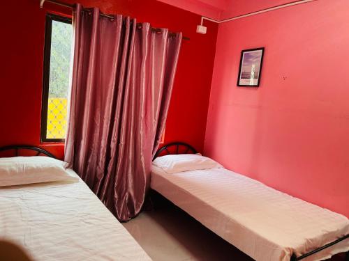 two beds in a room with red walls and a window at Grace house in Suva