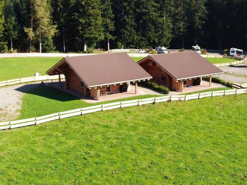 two wooden buildings in a field with a fence at Blockhaus Almhütte Wiesenglück in Glatten