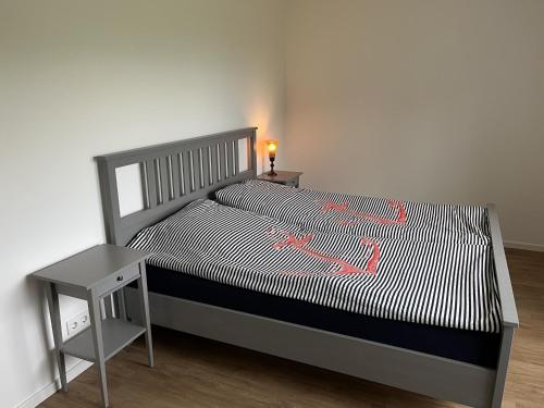 a bedroom with a bed with a nightstand and a table at Haacksen - modernes Ferienhaus mit 4 Schlafzimmern, Garten und Grill in Klappholz