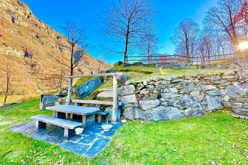una panchina seduta accanto a un muro di pietra di Rustico Alla Bolla - Happy Rentals a Frasco