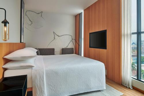 a bedroom with a white bed and a flat screen tv at Fairfield by Marriott Chow Kit Kuala Lumpur in Kuala Lumpur