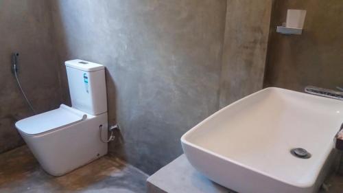 Łazienka z białą toaletą i umywalką w obiekcie Forest Edge Bungalow - Wilpattu w mieście Radagama