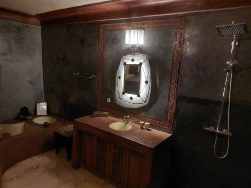 een badkamer met een wastafel, een spiegel en een bad bij Riad Jenaï L'Authentique in Marrakesh