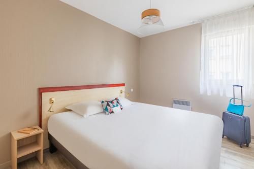 a bedroom with a large white bed and a window at Appart'City Classic Limoges in Limoges