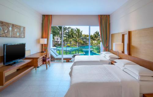 a hotel room with three beds and a television at Sheraton Hua Hin Resort & Spa in Cha Am