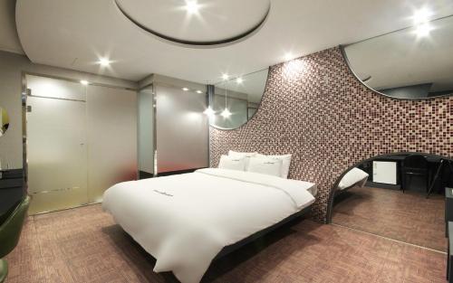 a bedroom with a large white bed and a brick wall at Rosso Hotel in Busan