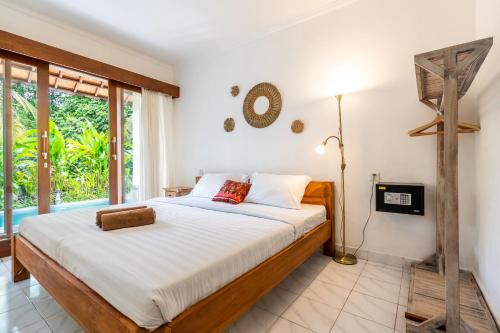 a bedroom with a bed and a large window at Uda Suite Guest House 2 in Ubud