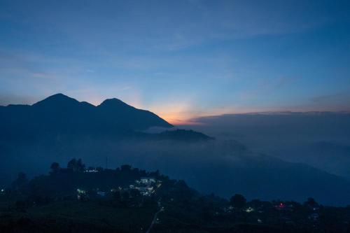 a view of a mountain with the sun setting behind the clouds at The Valle by Kondody Hotels in Munnar