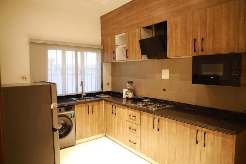 a kitchen with wooden cabinets and a washer and dryer at Omah Apartments in Abuja