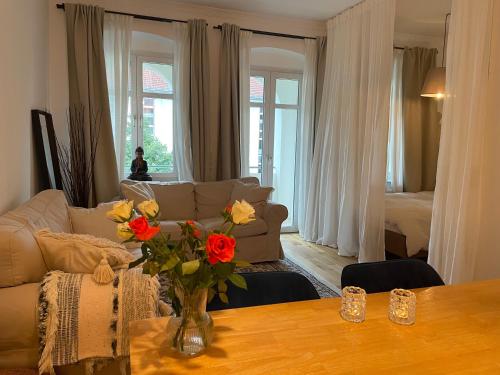 uma sala de estar com um sofá e uma mesa com flores em AnnApartment em Berlim